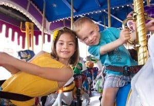 2 kids riding on a carousel