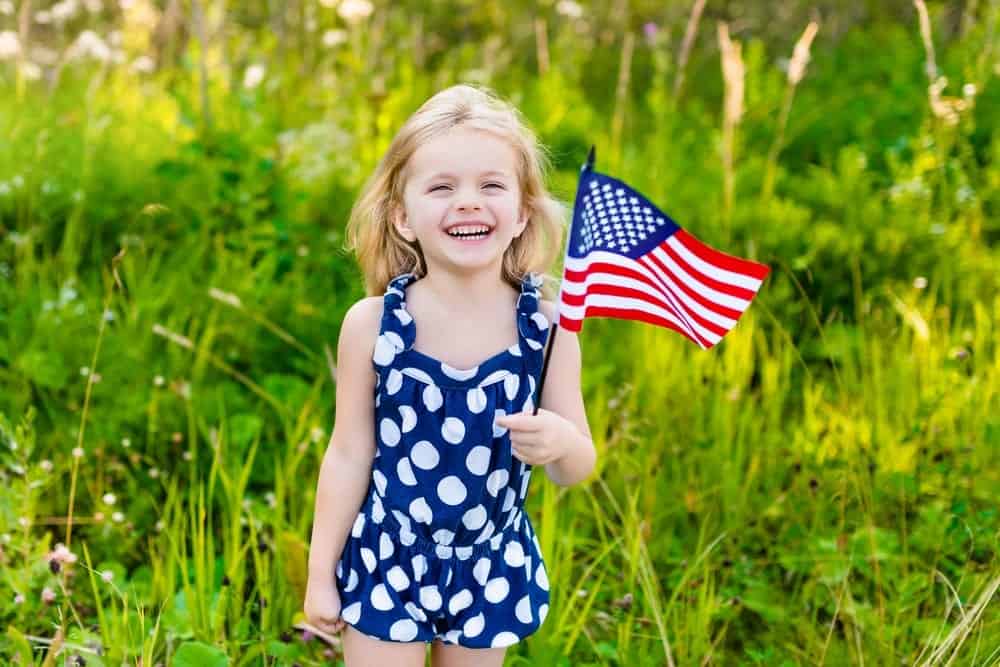smiling little girl carrying american flag while on vacation in Smoky Mountains