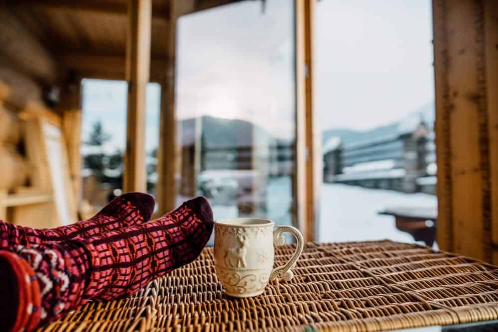 Person relaxes with hot cocoa at their cabin